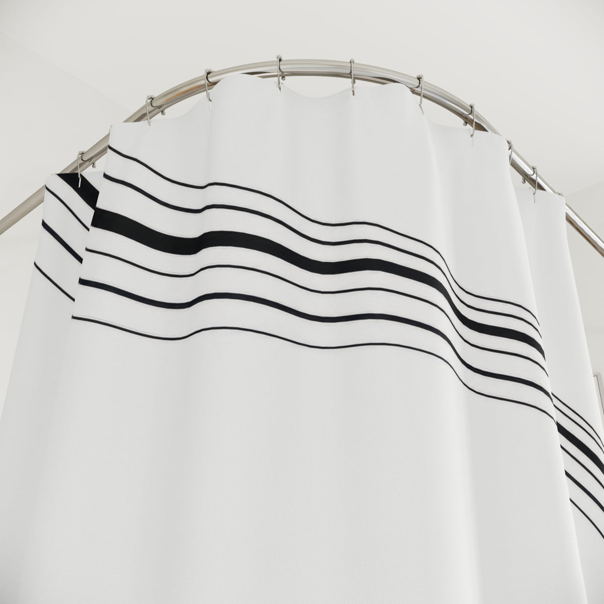 Parallel black stripes sweeping around an open white center shower curtain with close-up print, hooks, and folds