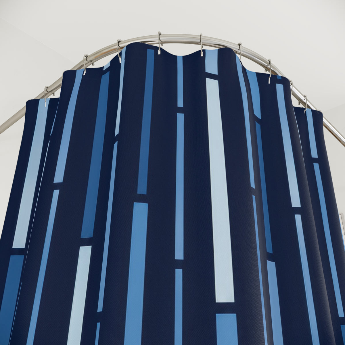 Blue vertical dash stripes on a midnight navy ground shower curtain with close-up print, hooks, and folds