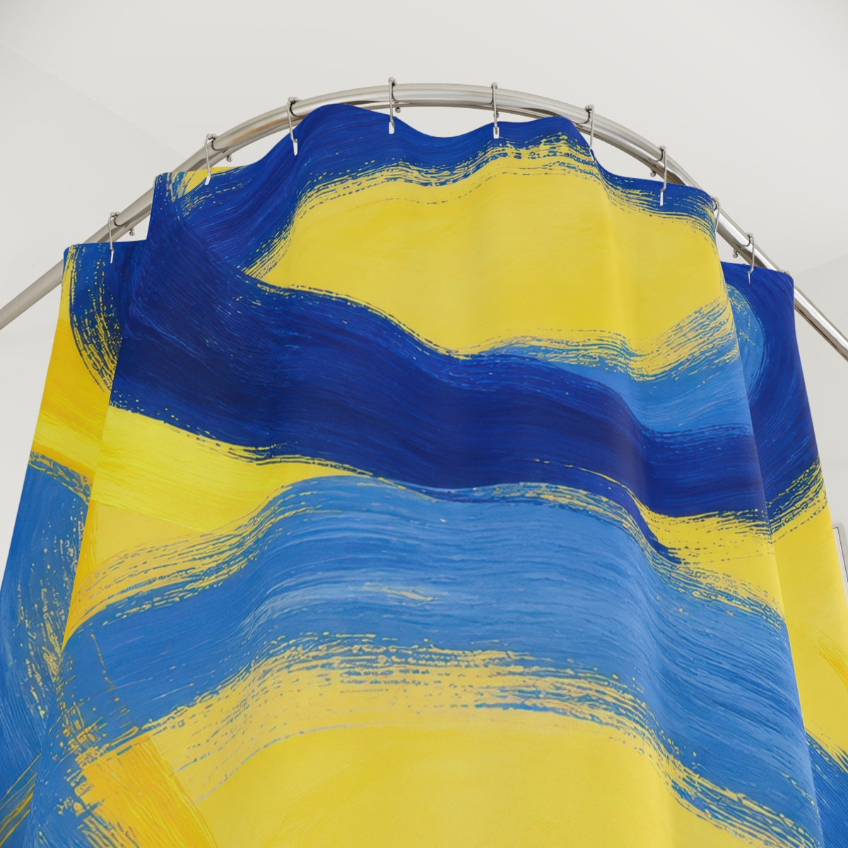 Blue brushstroke loops crossing a sunny yellow ground shower curtain with close-up print, hooks, and folds
