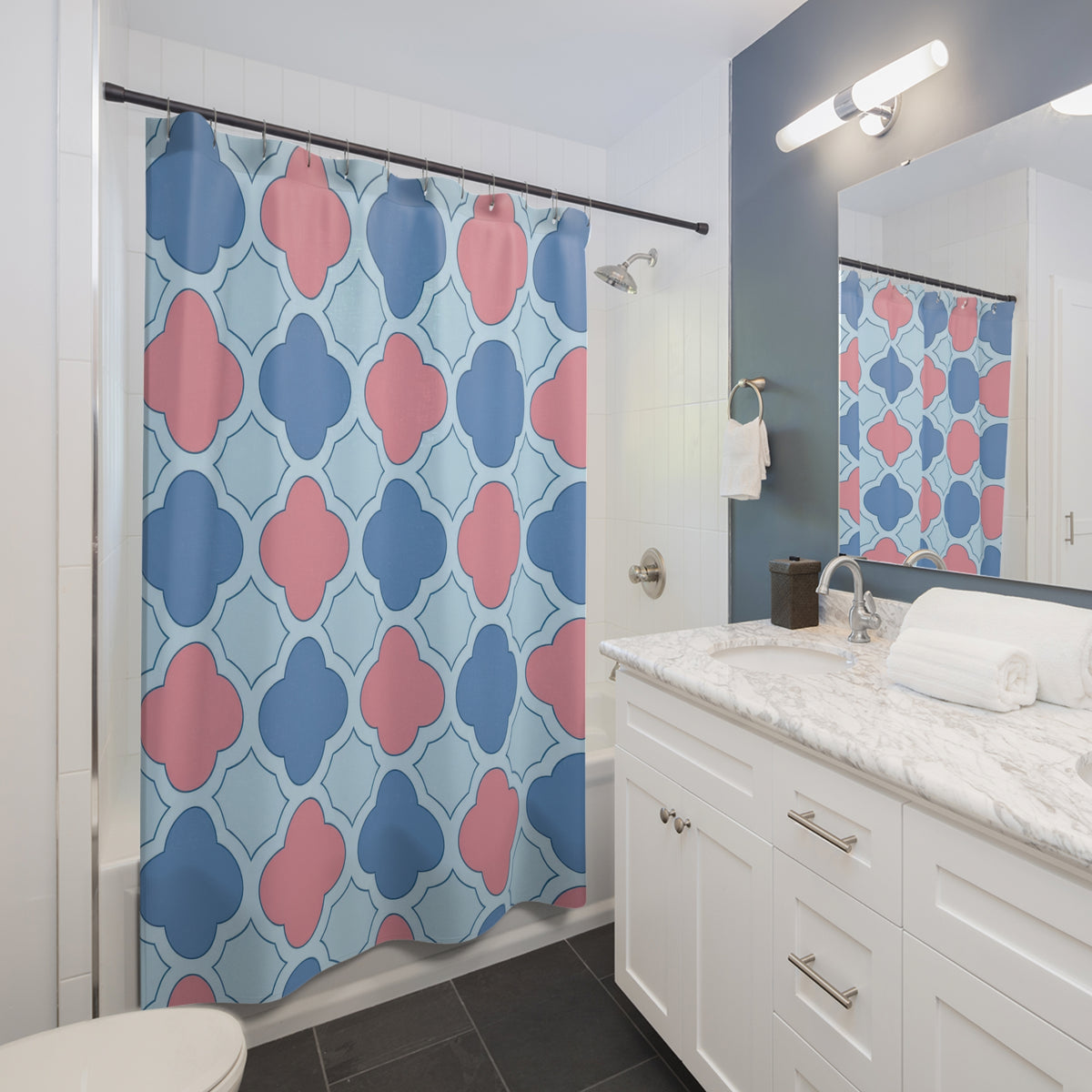 Blue and pink quatrefoils on a pale blue ground shower curtain beside a white vanity