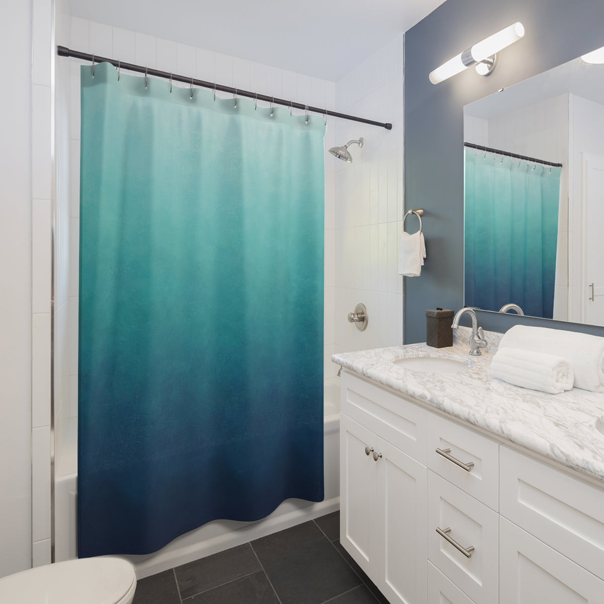 Aqua to deep blue ombre with teal midtones shower curtain beside a white vanity