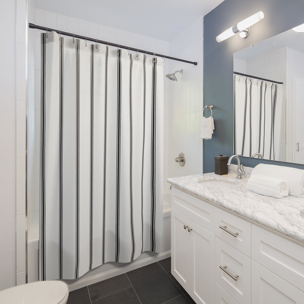Black vertical ticking triplets on a white ground shower curtain beside a white vanity