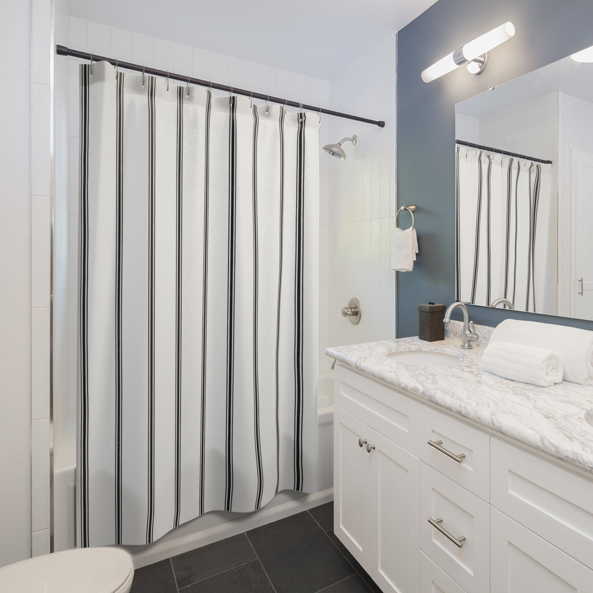 Black vertical ticking triplets on a white ground shower curtain beside a white vanity