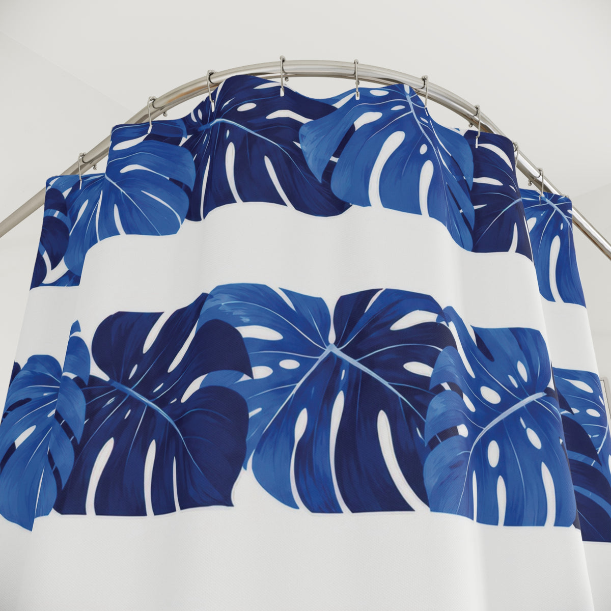 Cobalt monstera leaf bands alternating with white stripes shower curtain with close-up print, hooks, and folds
