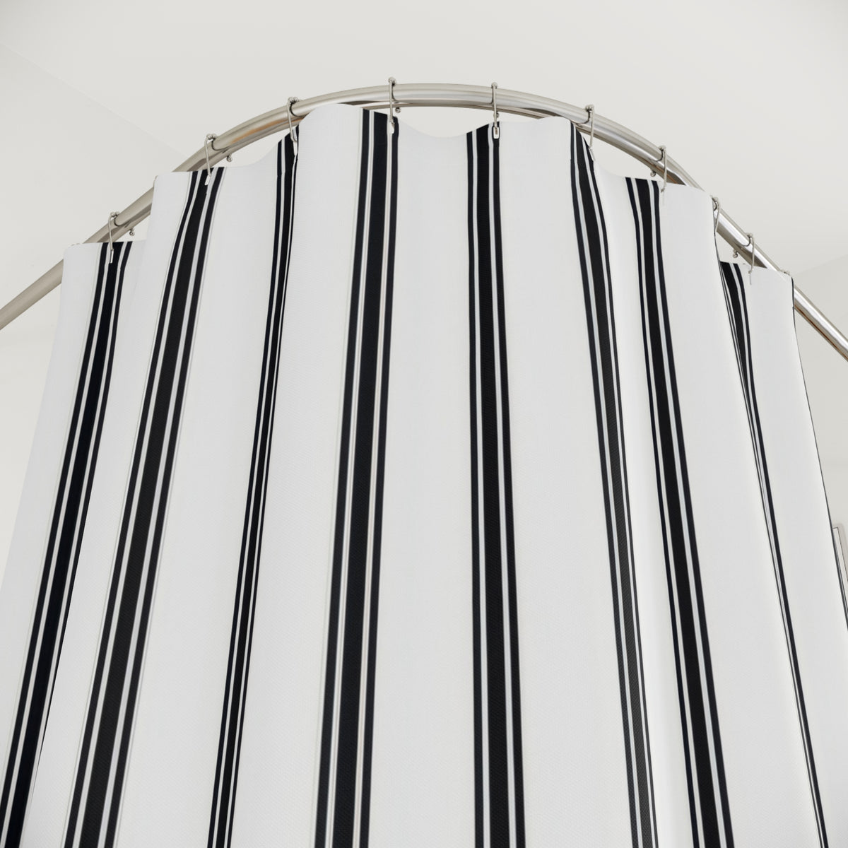 Fine black ticking stripe trios on white shower curtain with close-up print, hooks, and folds