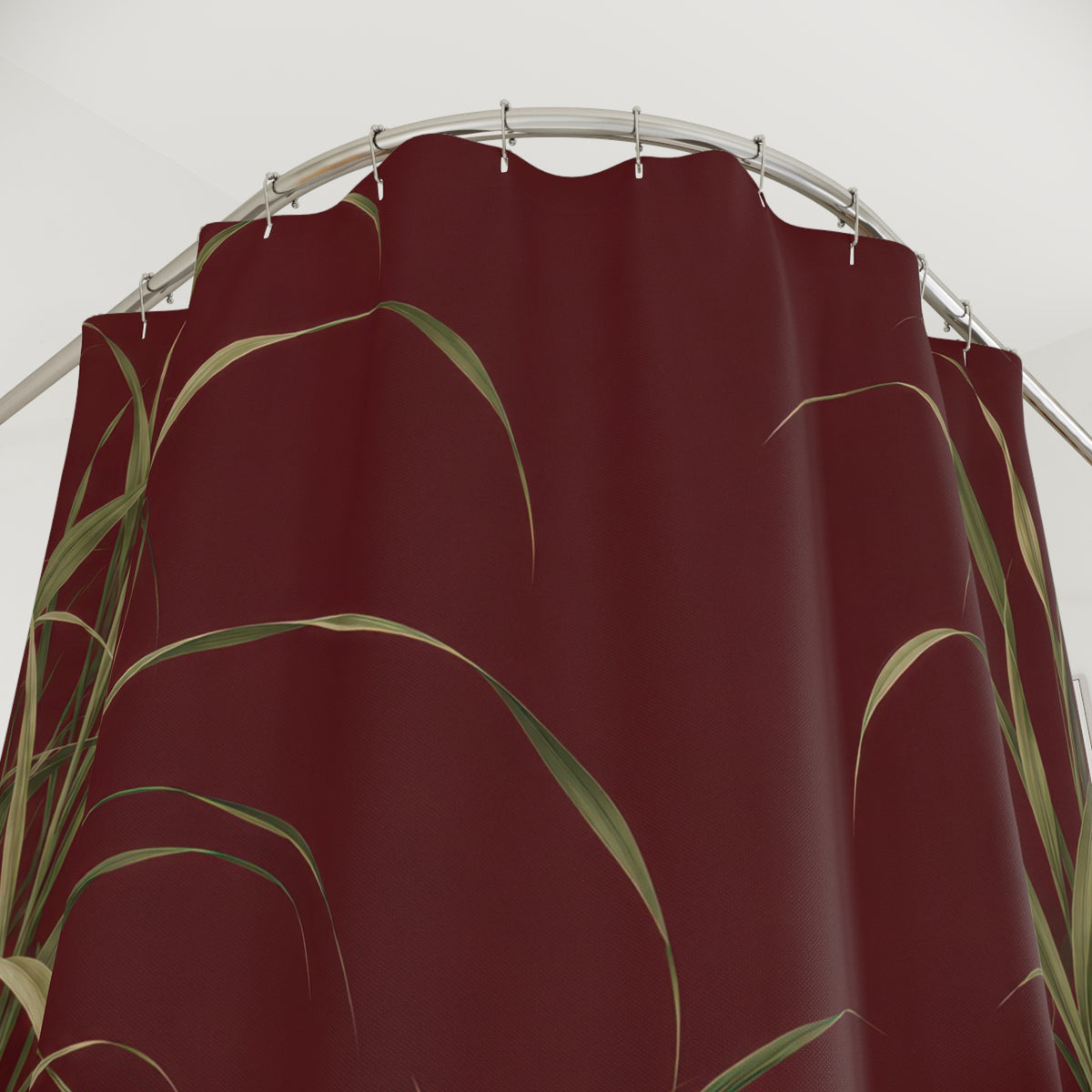 Arching sage and olive grasses on an open maroon field shower curtain with close-up print, hooks, and folds