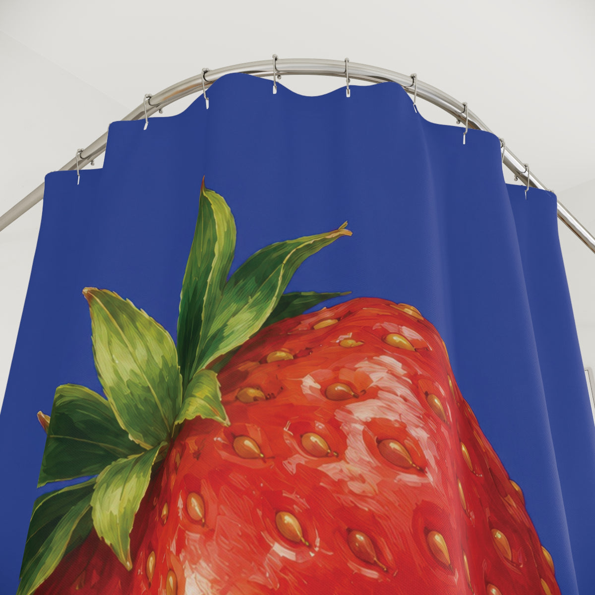 Single red strawberry with green crown on cobalt blue shower curtain with close-up print, hooks, and folds