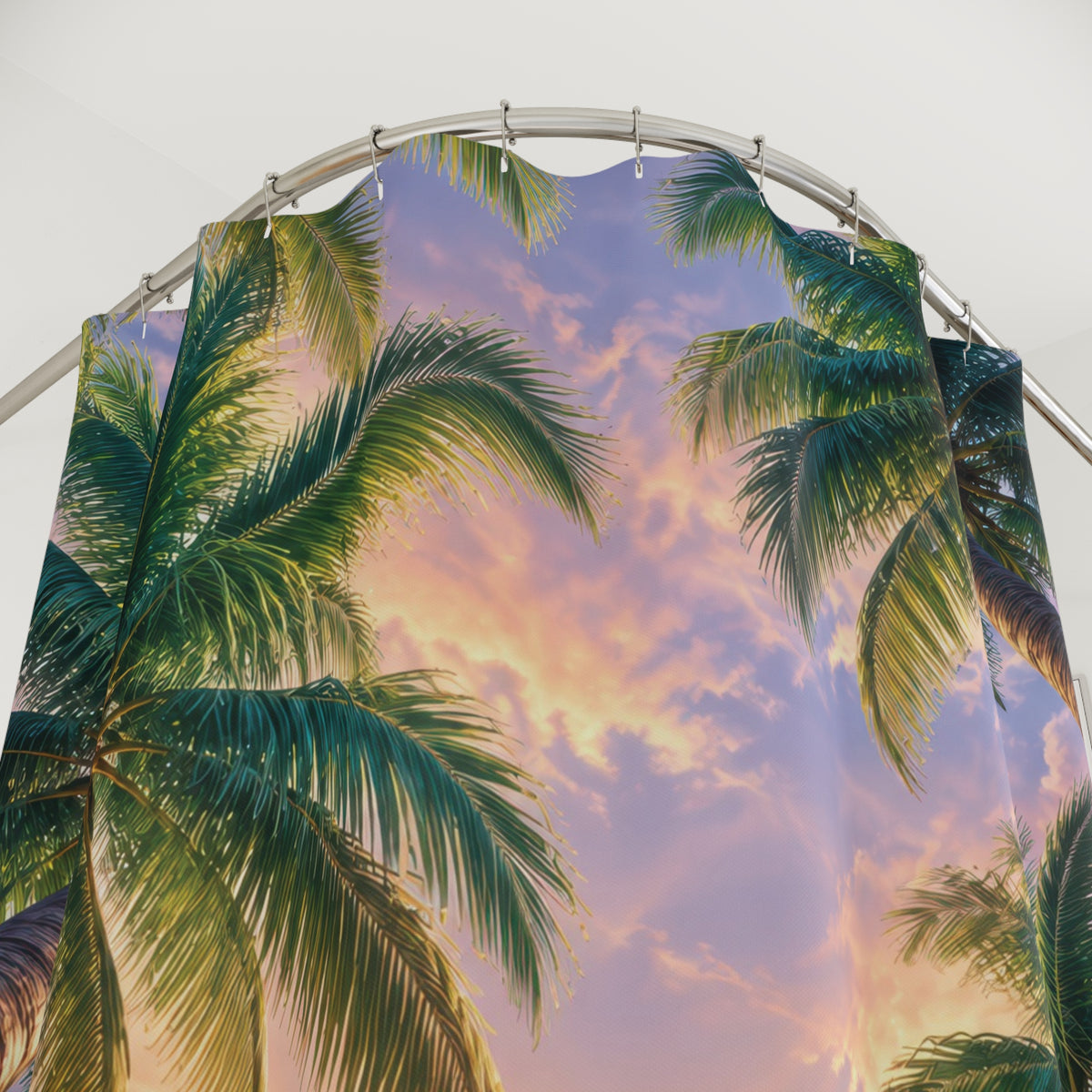 Green palm canopy around a pink and lavender sunset sky shower curtain with close-up print, hooks, and folds