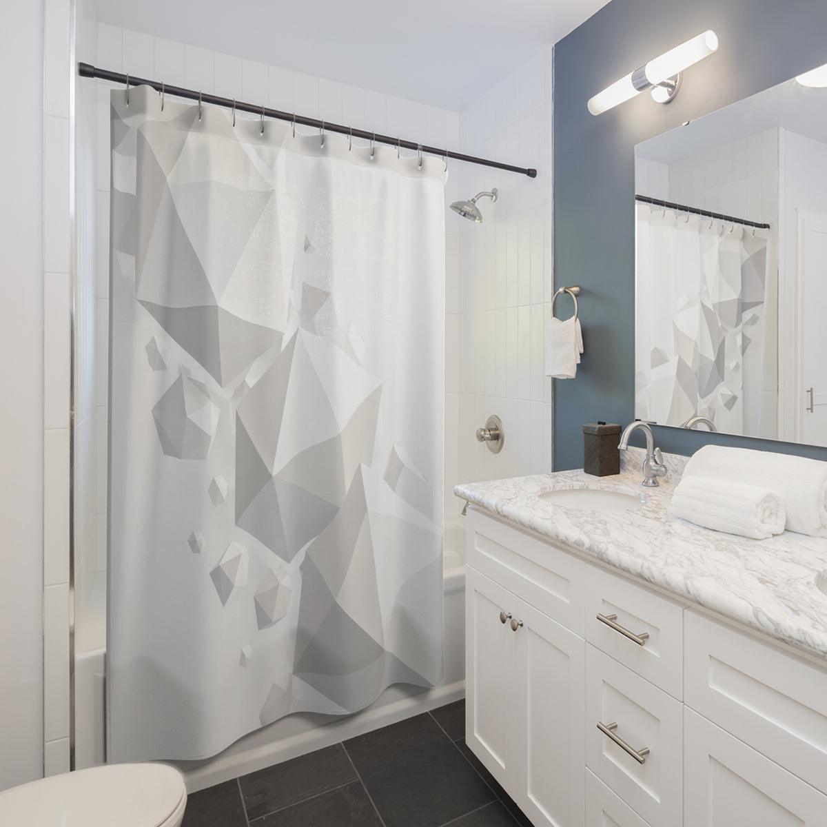 Floating white polyhedra cascading across a pale mist-gray field shower curtain beside a white vanity