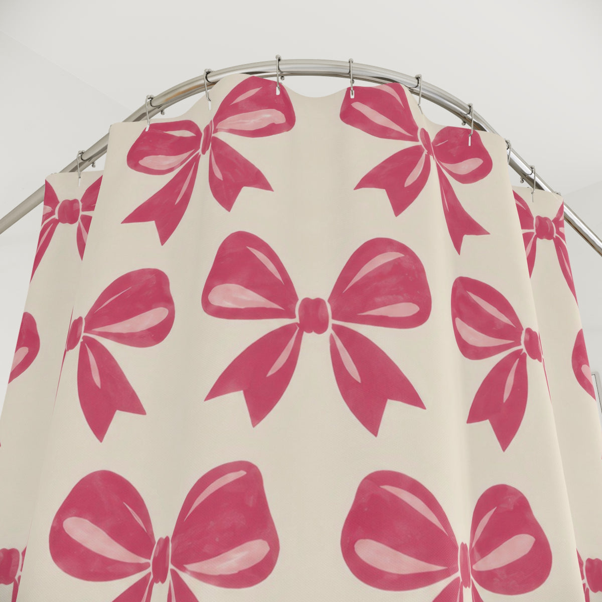 Pink bow pattern with raspberry loops on warm cream shower curtain with close-up print, hooks, and folds