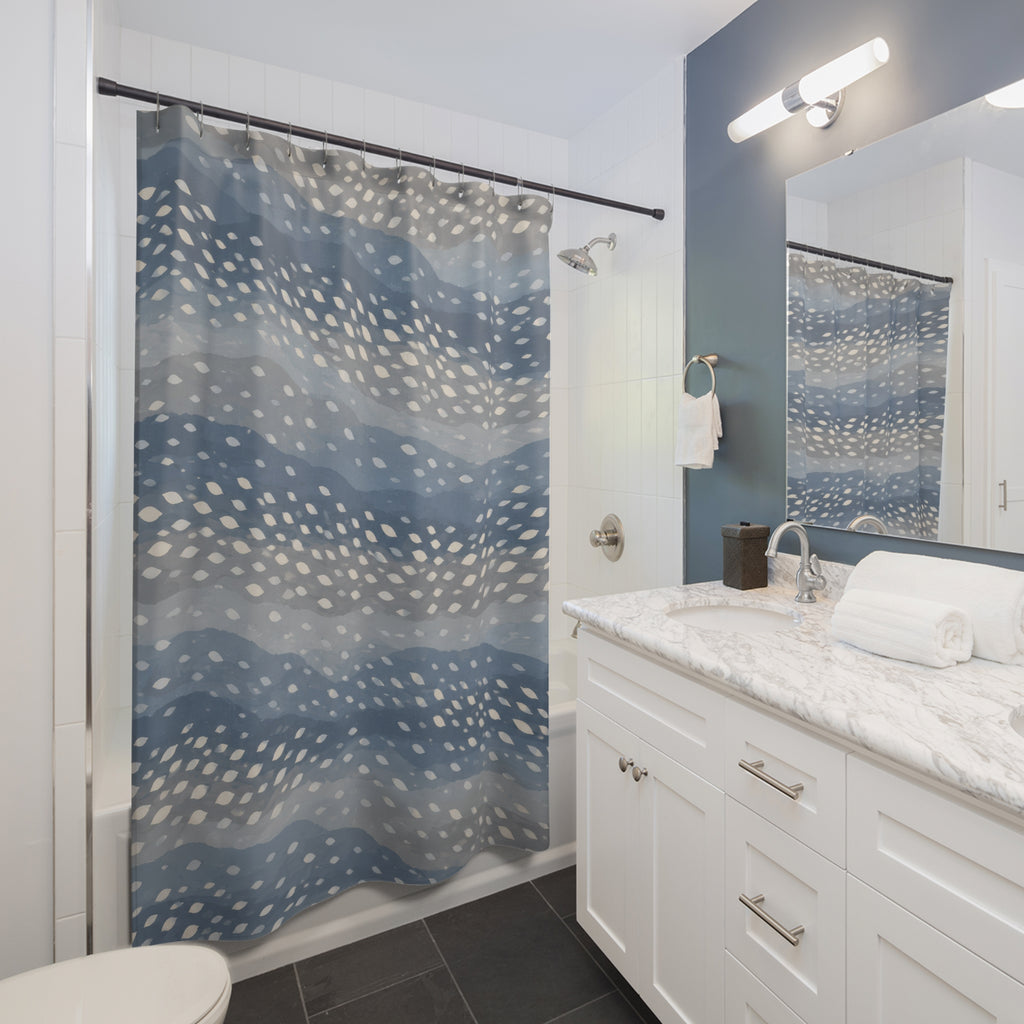 Ivory fawn spots across wavy dusty blue and grey bands shower curtain beside a white vanity