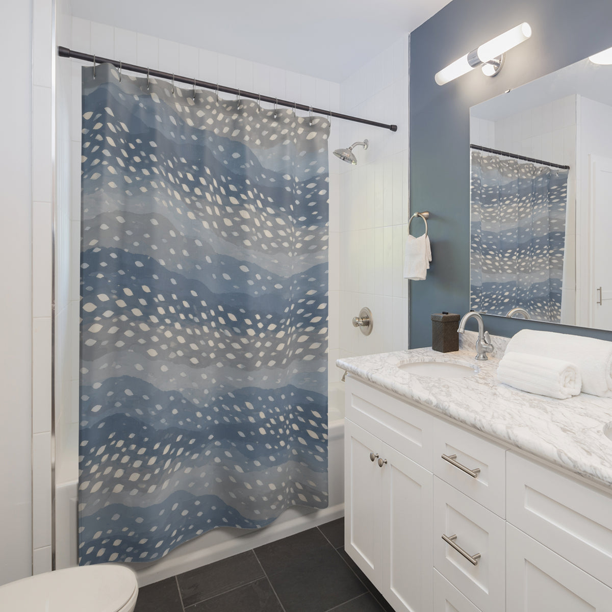 Ivory fawn spots across wavy dusty blue and grey bands shower curtain beside a white vanity