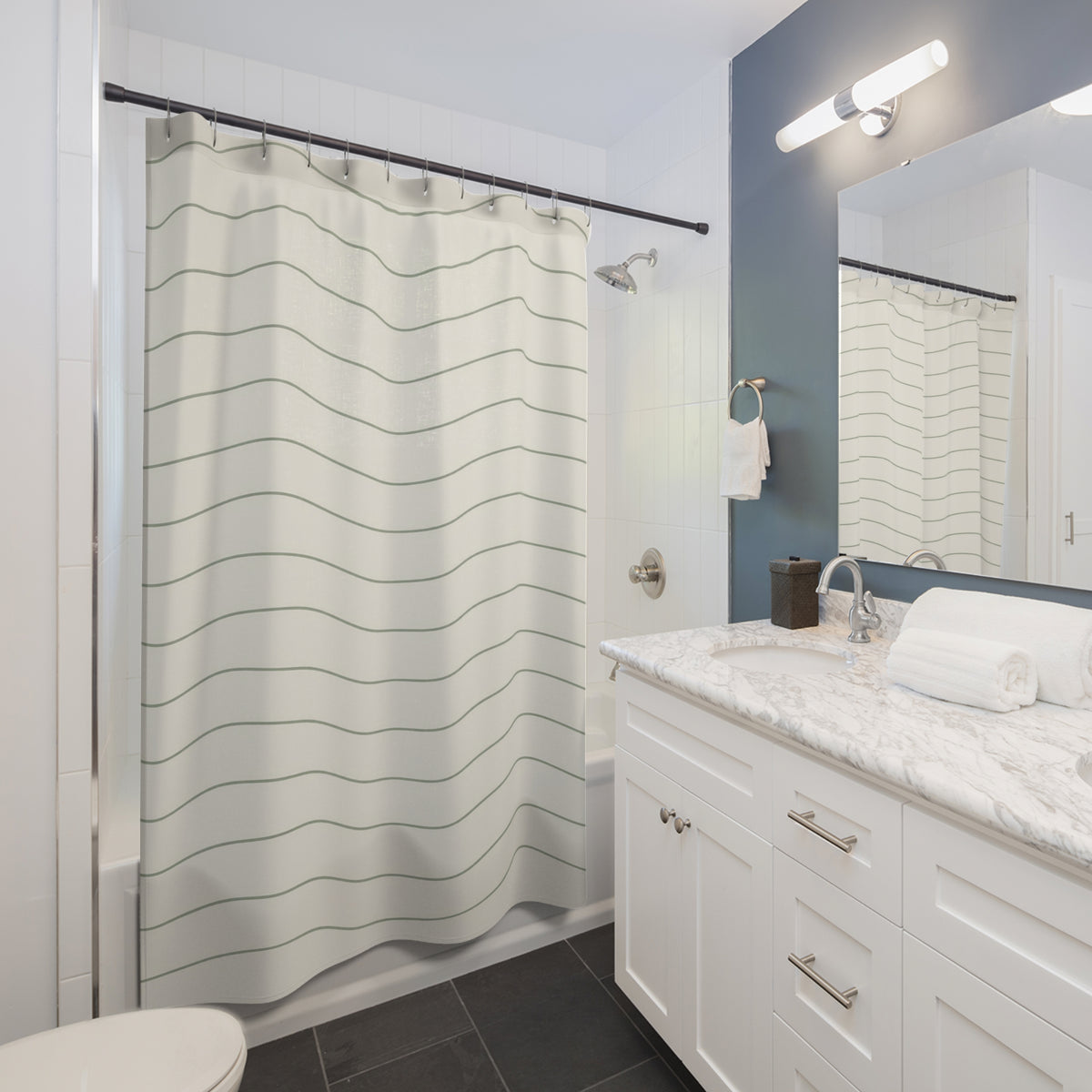 Thin sage green wave lines on warm ivory shower curtain beside a white vanity