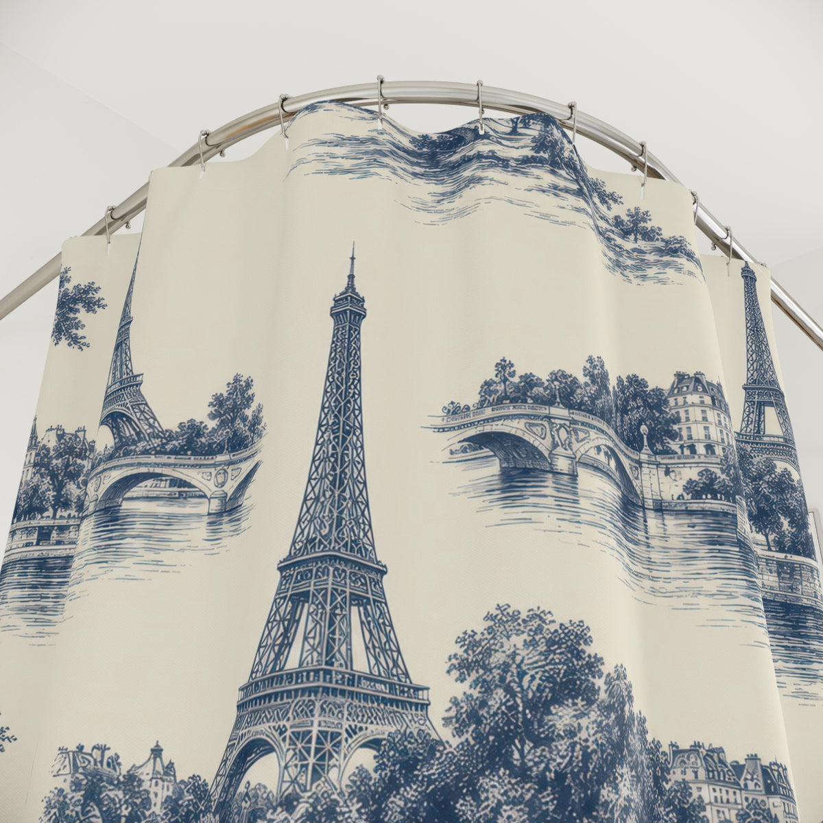 Indigo Eiffel Towers and river bridges on warm ivory shower curtain with close-up print, hooks, and folds