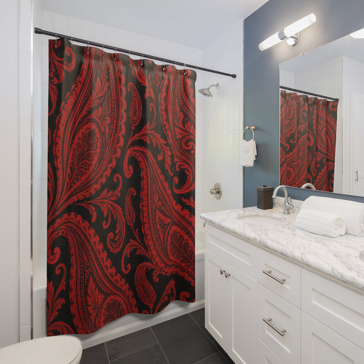 Red paisley teardrops and curling scrollwork on black shower curtain beside a white vanity