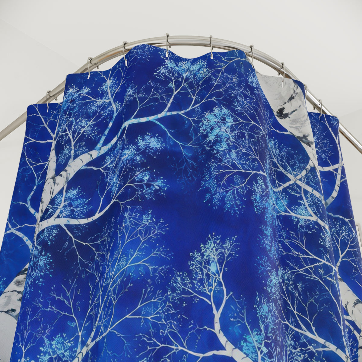 White birch canopy against cobalt blue shower curtain with close-up print, hooks, and folds