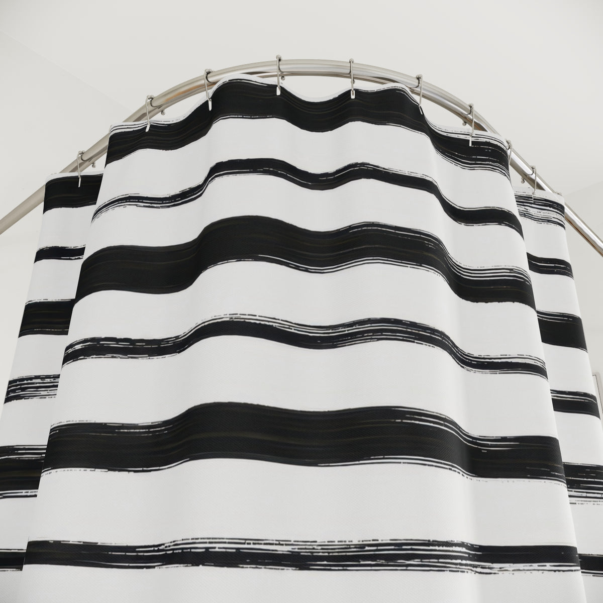 Horizontal black brush stripes with dry ink edges on white shower curtain with close-up print, hooks, and folds