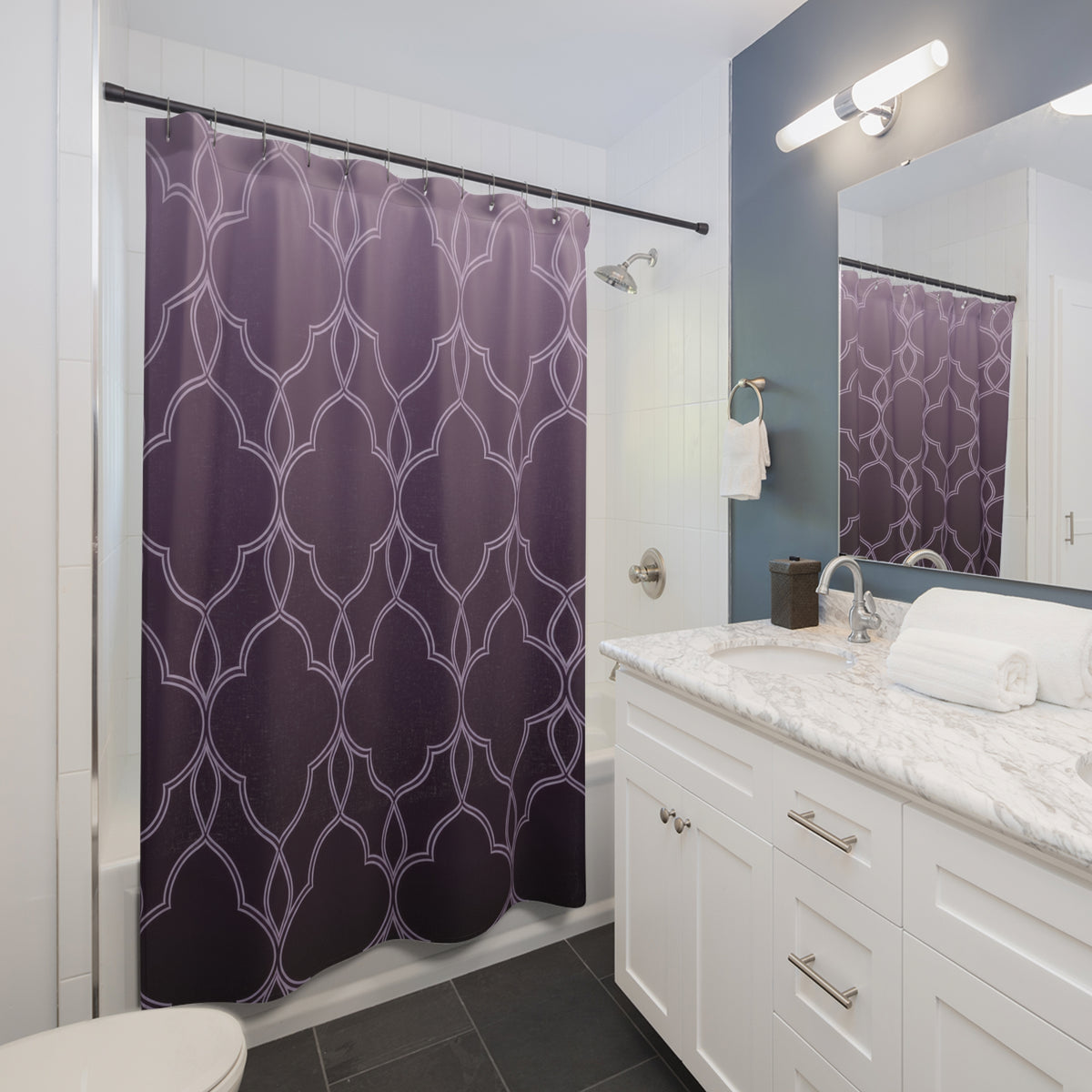 Pale quatrefoil tracery over a lavender to plum ombre shower curtain beside a white vanity
