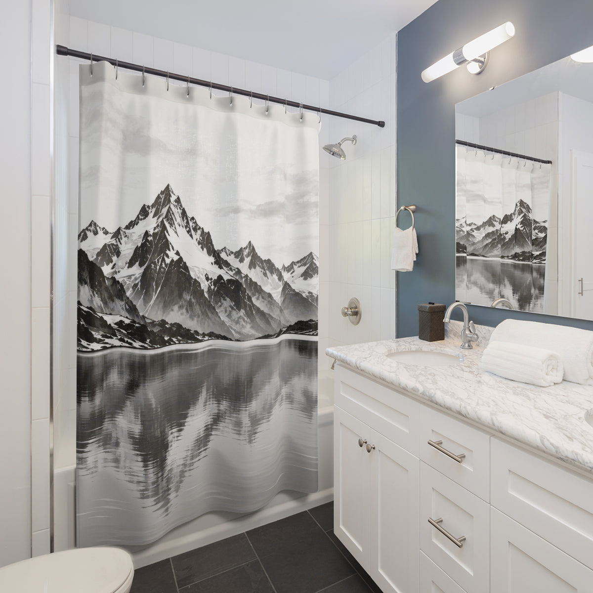 Snowy black and gray mountains reflected in a pale lake shower curtain beside a white vanity
