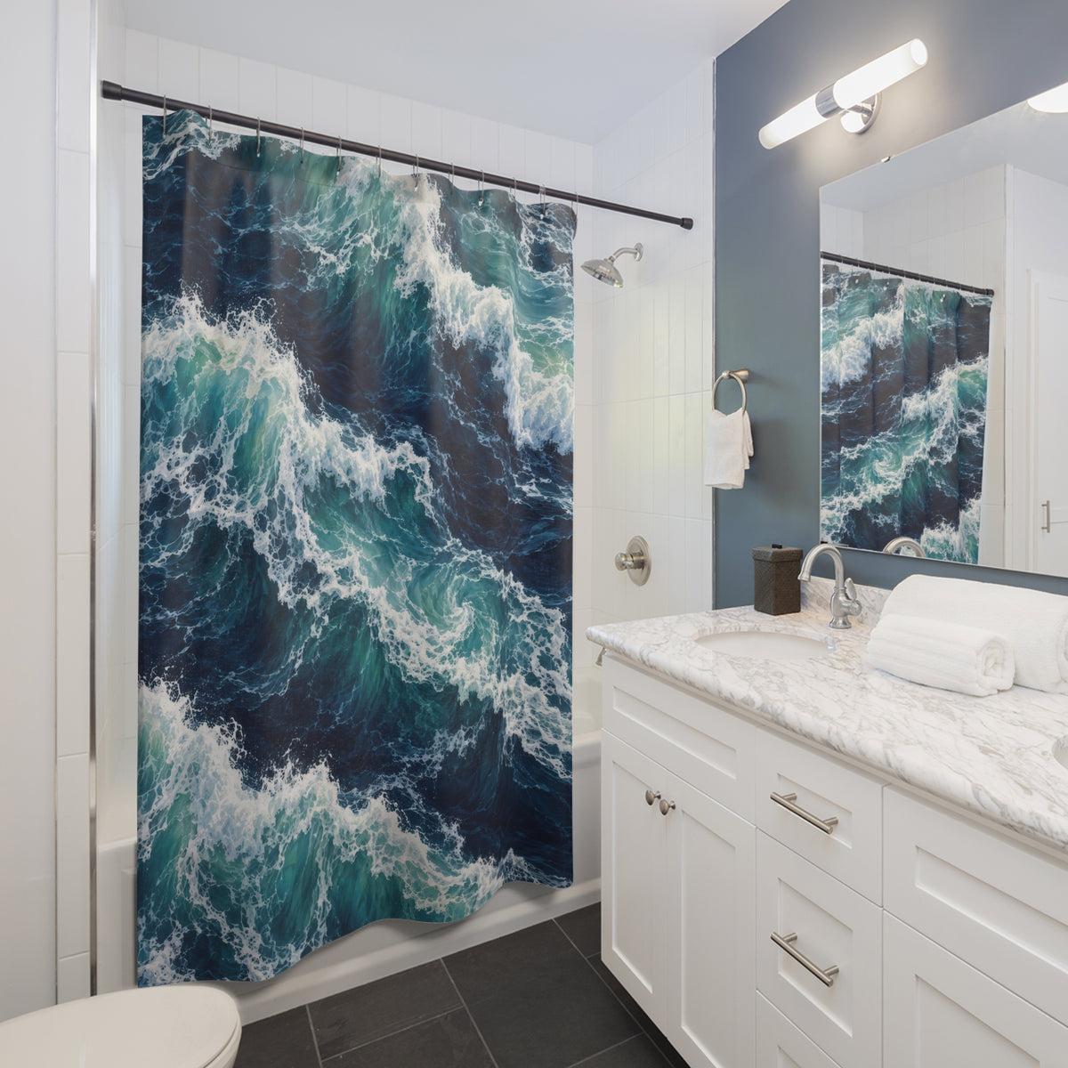 Turquoise breaking waves and white sea foam on navy water shower curtain beside a white vanity