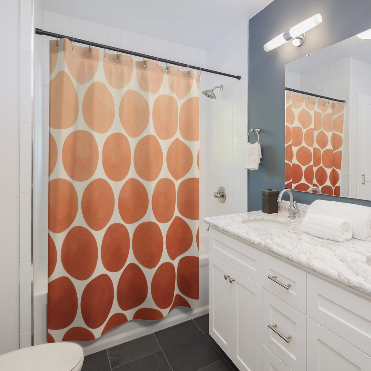 Peach to terracotta ombre dots on ivory shower curtain beside a white vanity