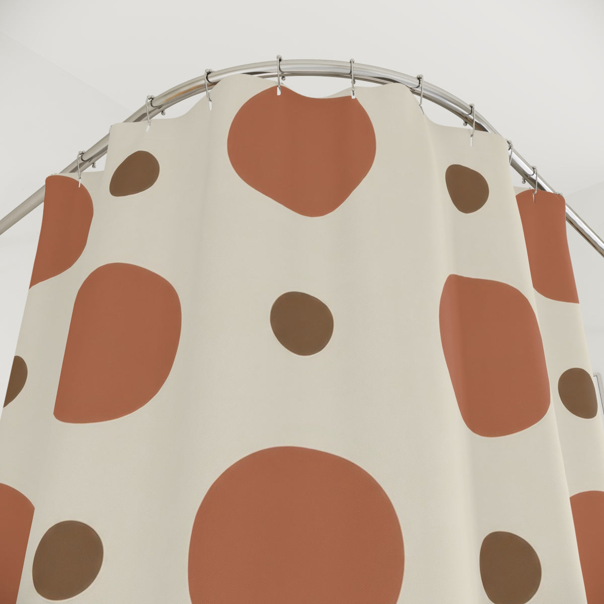 Large terracotta circles and small brown dots on cream shower curtain with close-up print, hooks, and folds