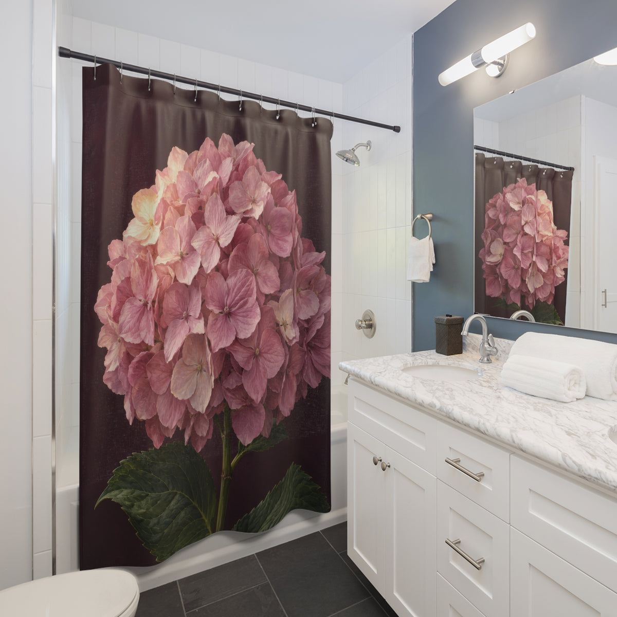 One pink hydrangea bloom with green leaves on aubergine shower curtain beside a white vanity