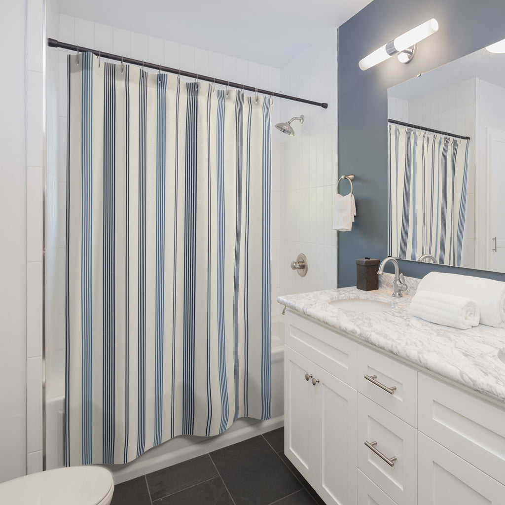 Navy and slate-blue pinstripe groups on warm ivory shower curtain beside a white vanity