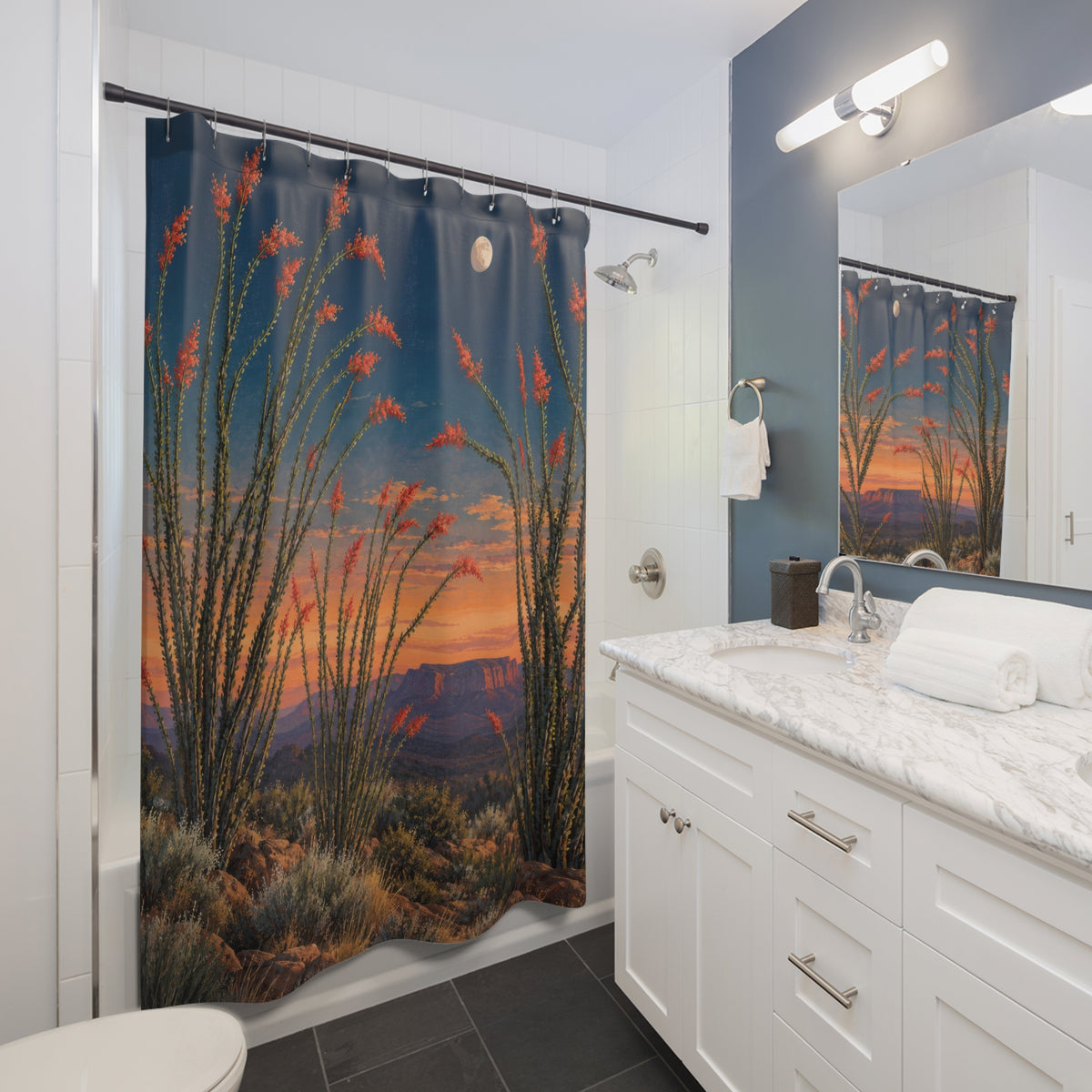 Red ocotillo flowers beneath a moon in blue and apricot sky shower curtain beside a white vanity