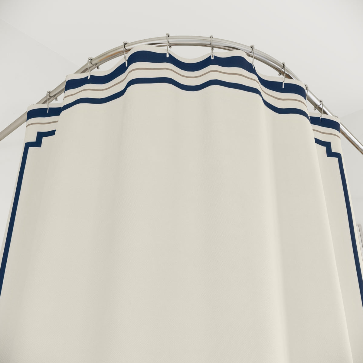 Navy stepped borders around an ivory center shower curtain with close-up print, hooks, and folds
