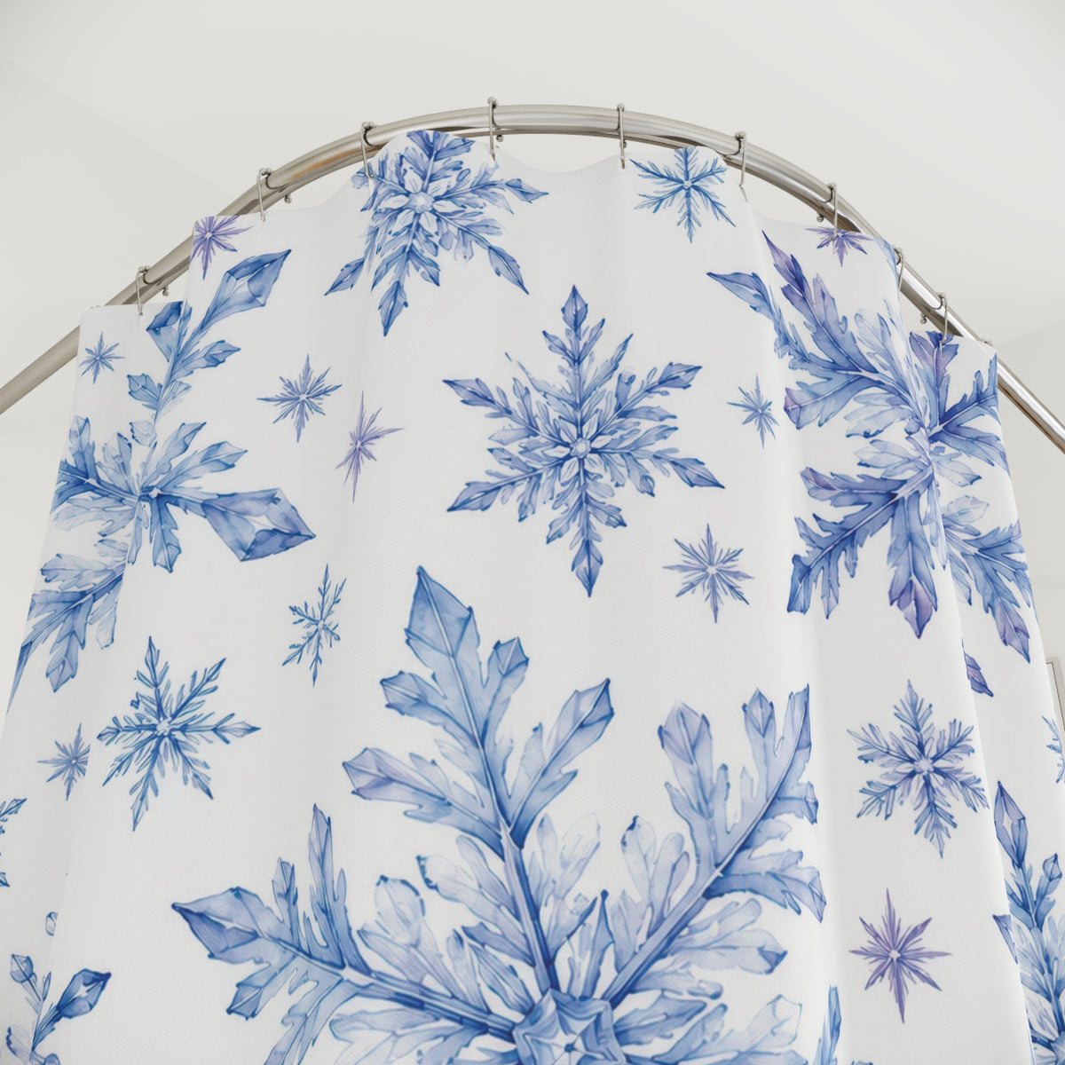Blue and lilac watercolor snowflakes on white shower curtain with close-up print, hooks, and folds