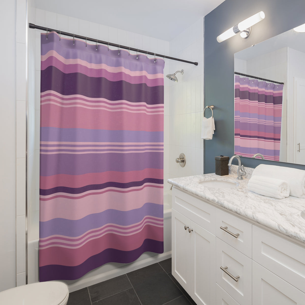 Horizontal stripes in dusty rose pink, lavender and plum shower curtain beside a white vanity