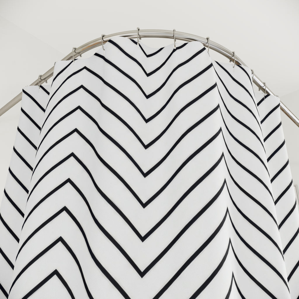 Thin black chevron zigzags on an open white ground shower curtain with close-up print, hooks, and folds