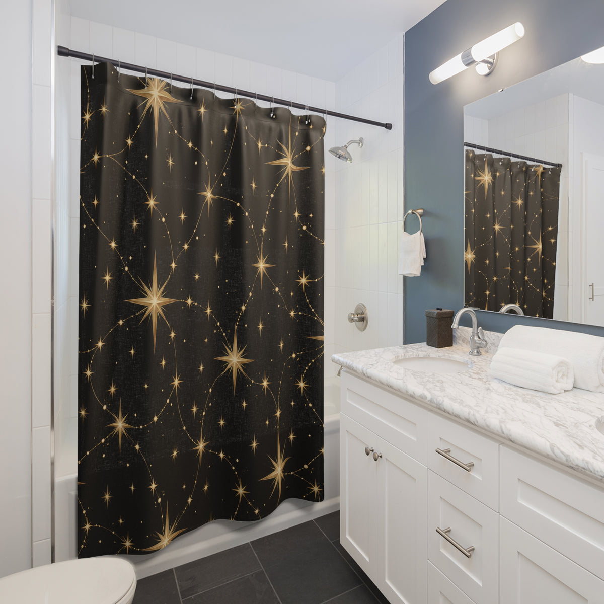Gold radiant stars linked by fine paths on black shower curtain beside a white vanity