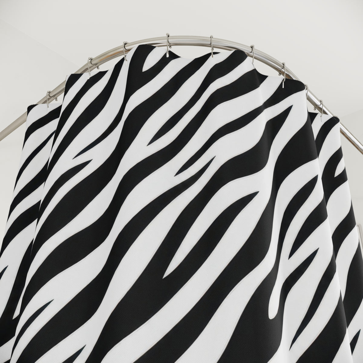 Diagonal black zebra stripes tapering across white shower curtain with close-up print, hooks, and folds
