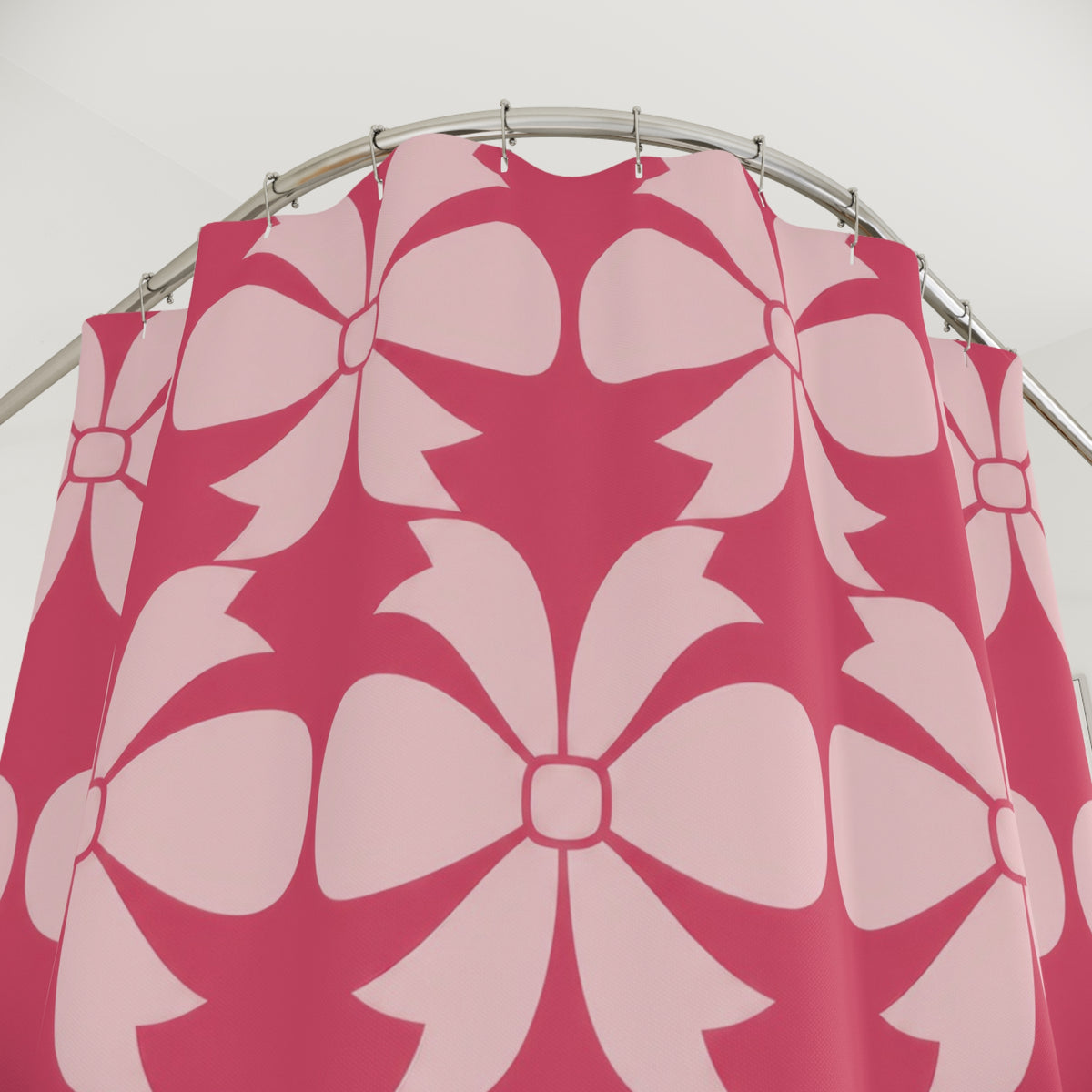 Pale pink bow ornaments on strawberry pink shower curtain with close-up print, hooks, and folds