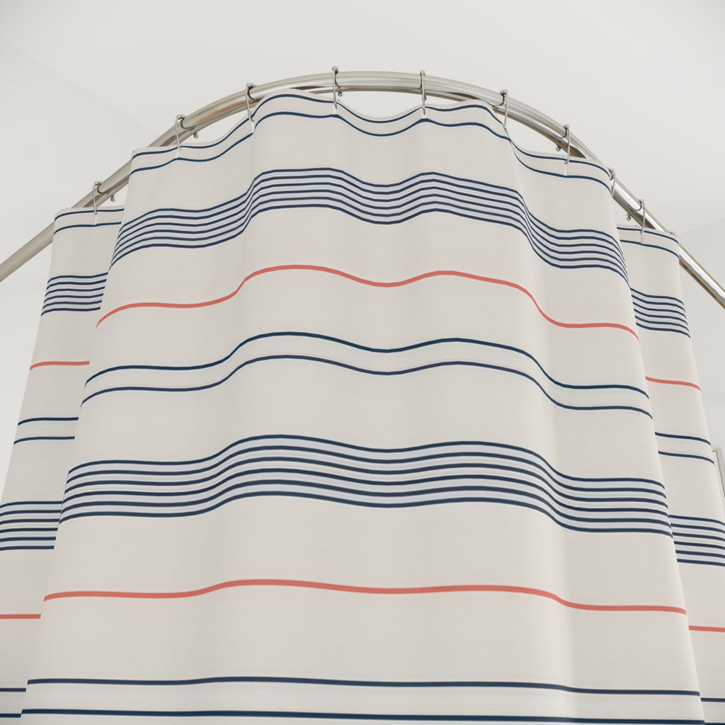 Fine navy line bands and single coral stripes on cream shower curtain with close-up print, hooks, and folds