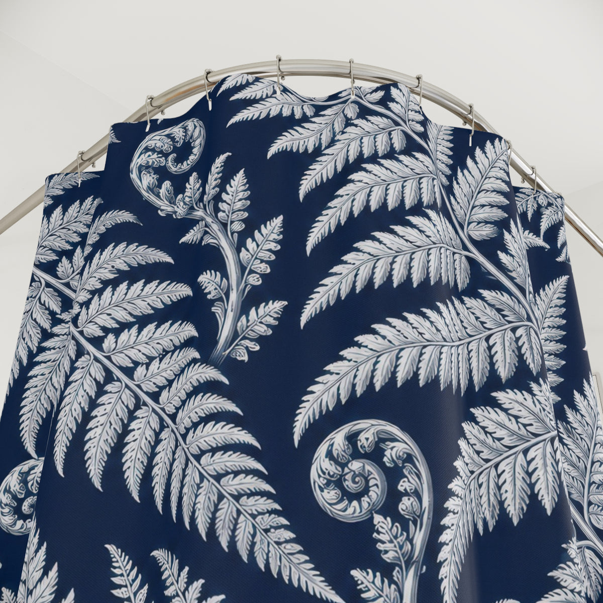 White fern fronds and curled fiddleheads on deep navy shower curtain with close-up print, hooks, and folds