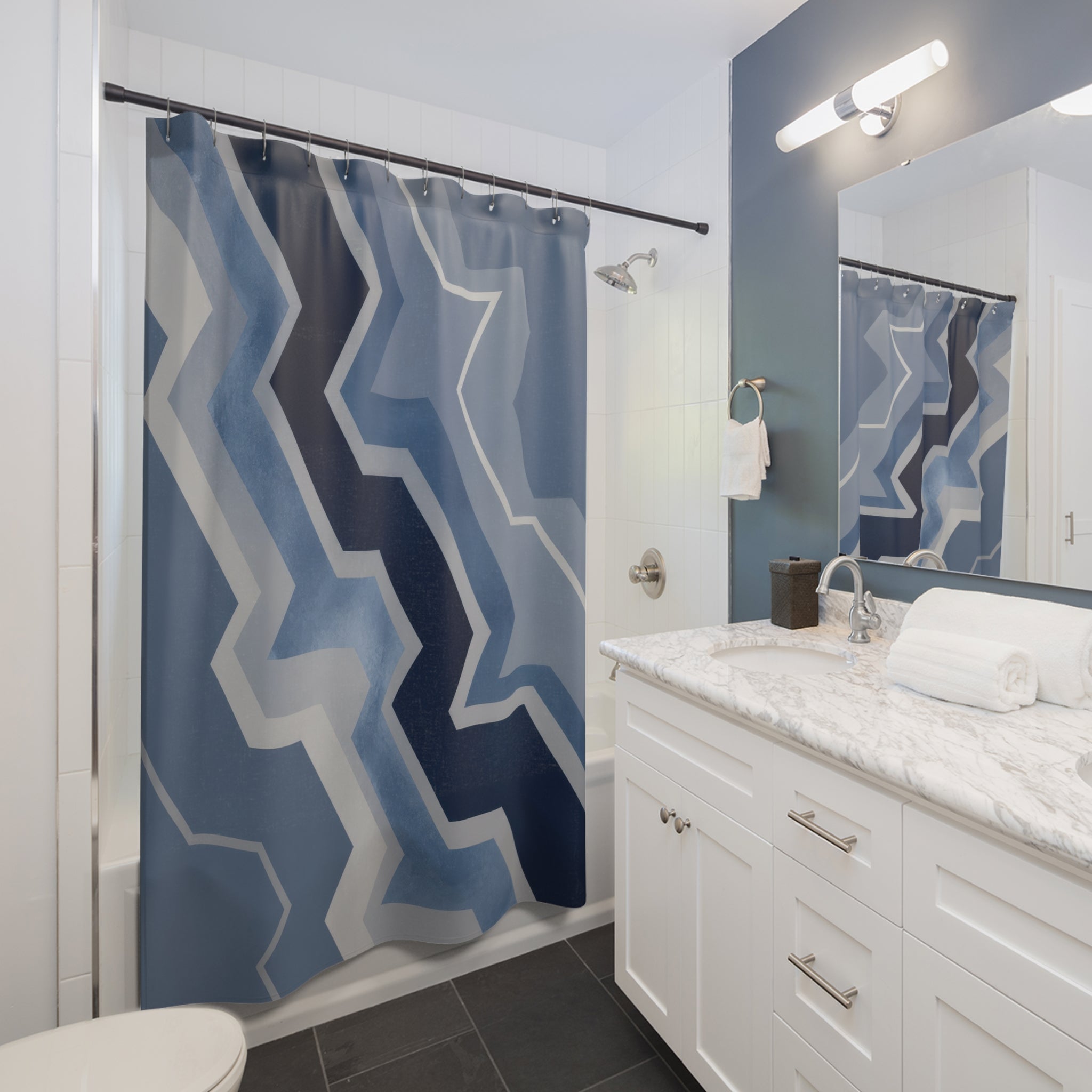 Blue and grey offset zigzag chevrons cascading diagonally shower curtain beside a white vanity