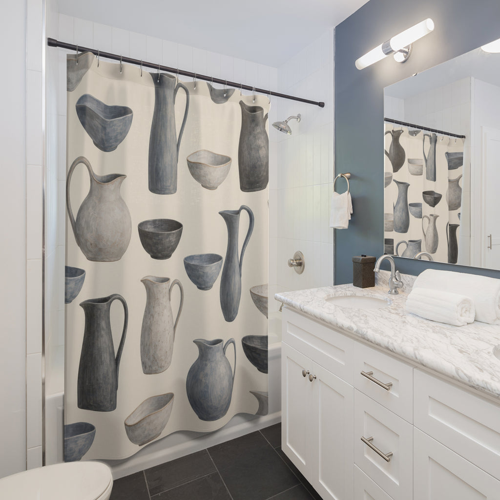 Blue-gray pitchers and bowls with charcoal accents on cream shower curtain beside a white vanity