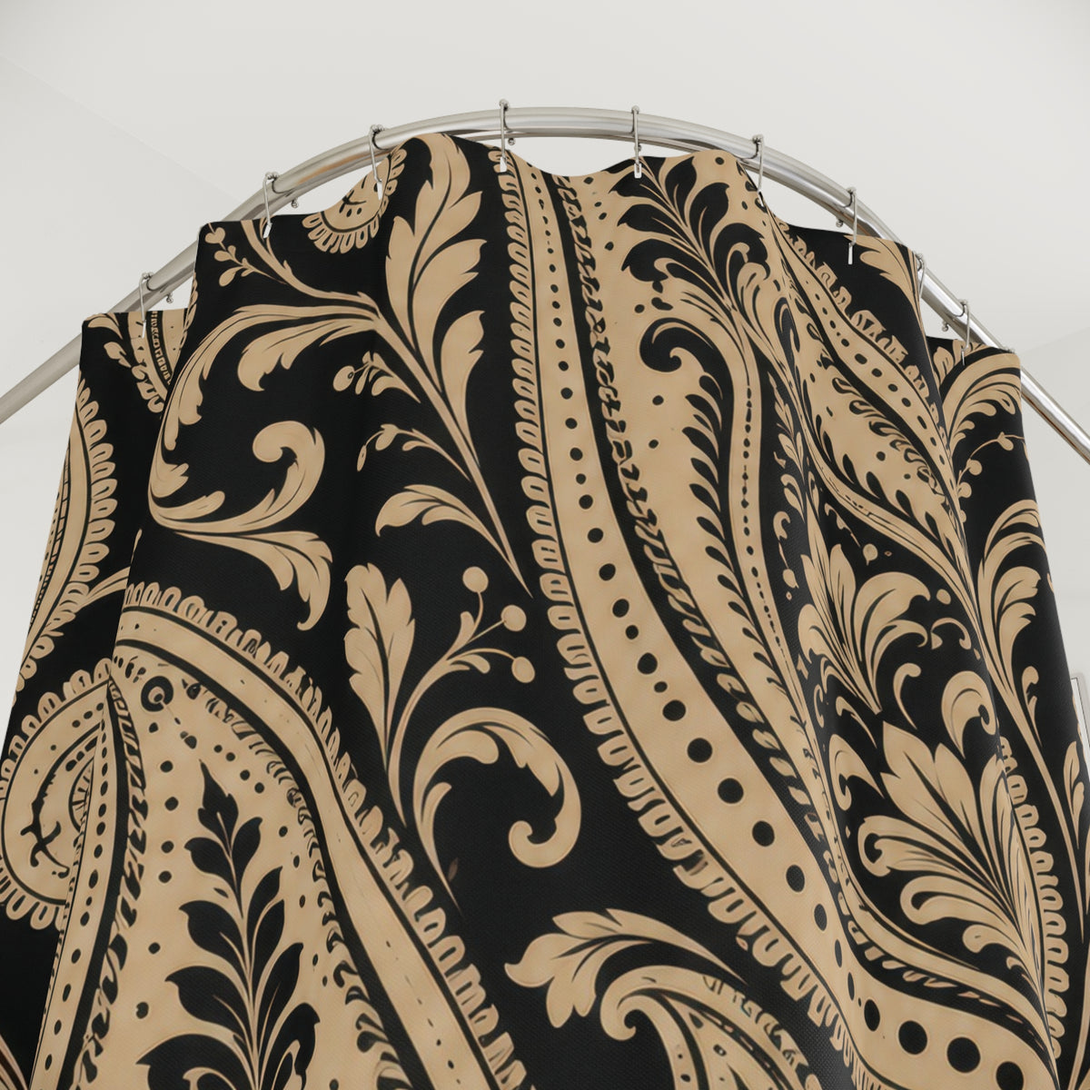 Beige and black paisley scrollwork shower curtain with close-up print, hooks, and folds