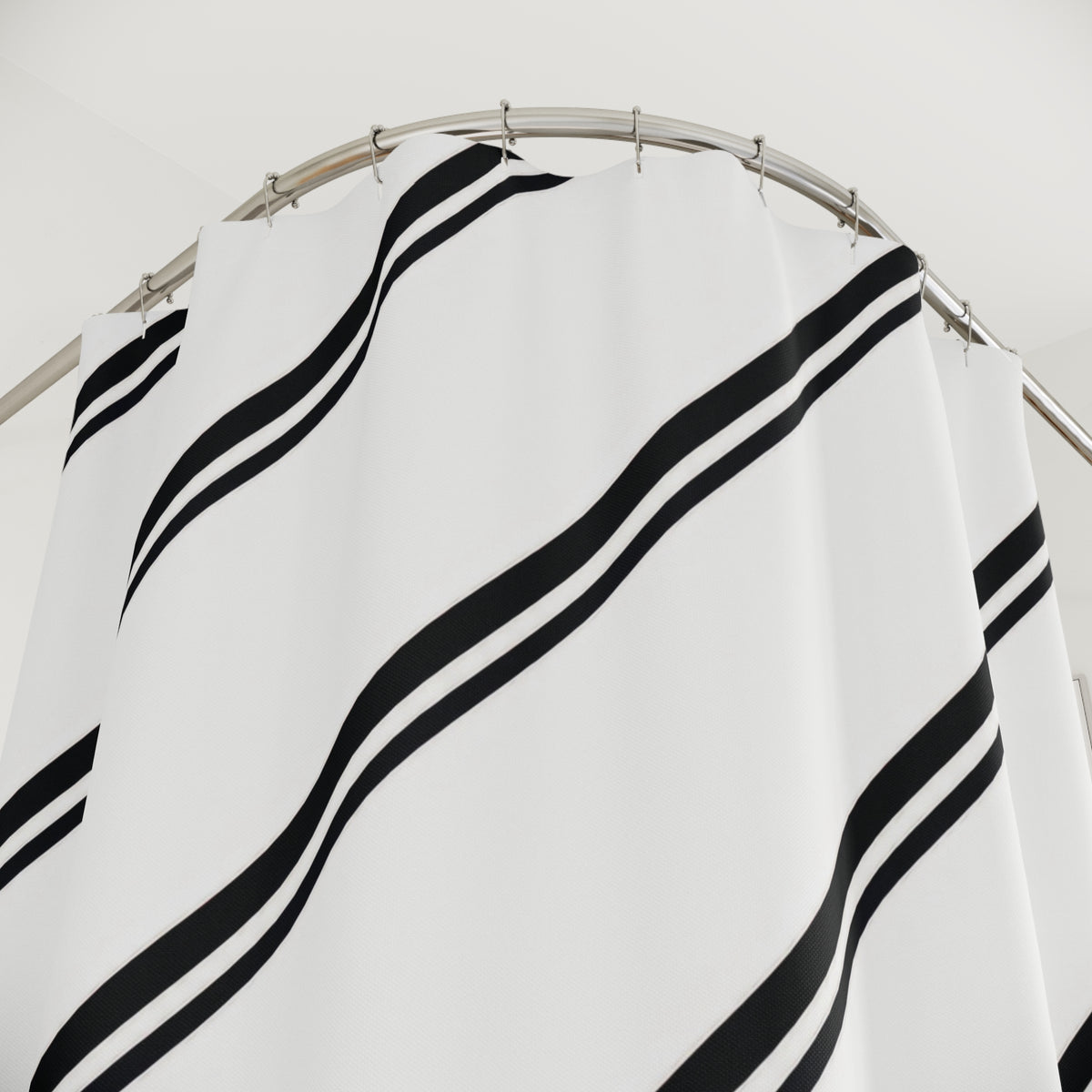 Paired black diagonal stripes across a white field shower curtain with close-up print, hooks, and folds