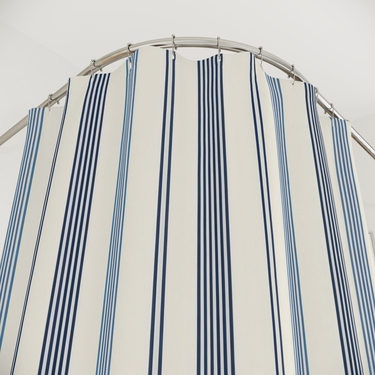 Navy and slate-blue pinstripe groups on warm ivory shower curtain with close-up print, hooks, and folds