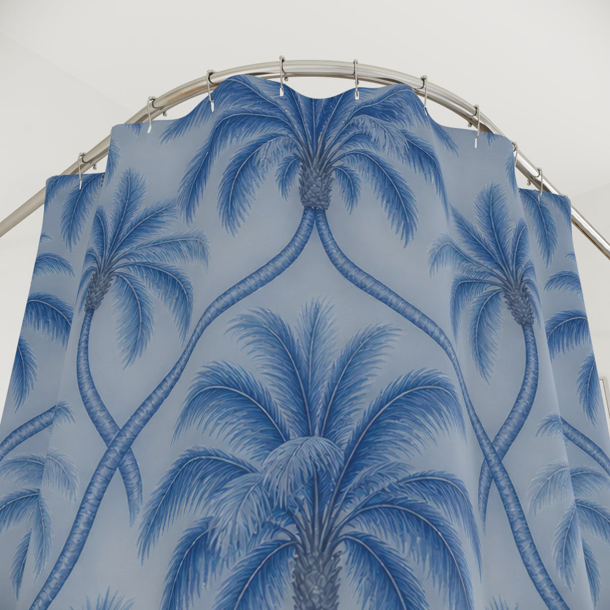 Blue palm trees with interlaced trunks on pale blue shower curtain with close-up print, hooks, and folds