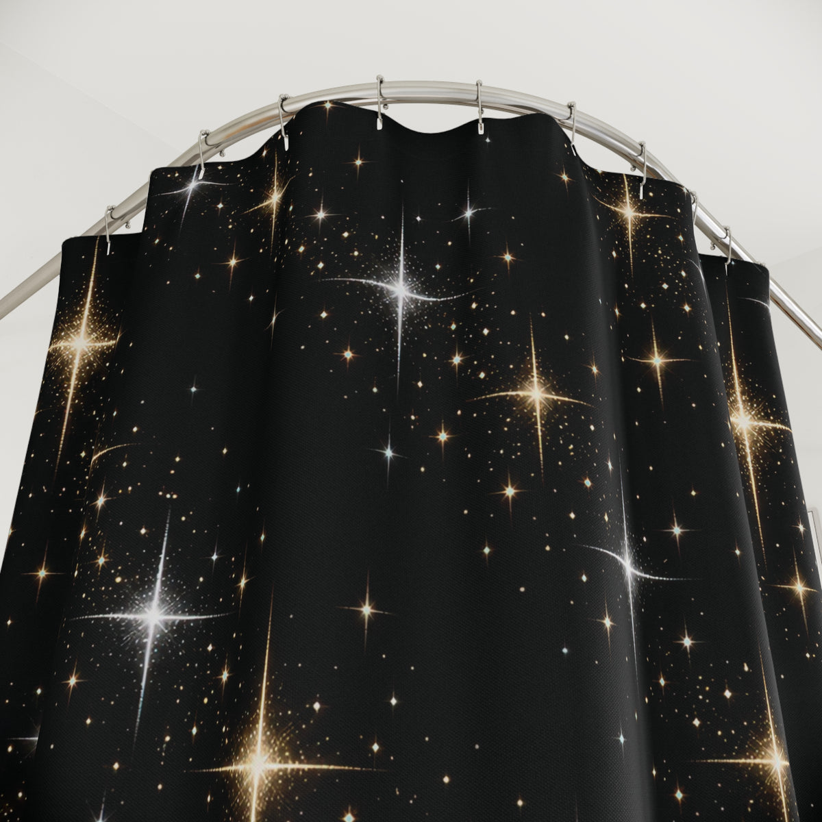 Gold and silver-colored stars on black shower curtain with close-up print, hooks, and folds