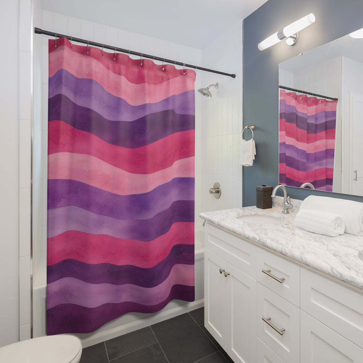 Wavy watercolor stripes in pink, lavender and plum shower curtain beside a white vanity
