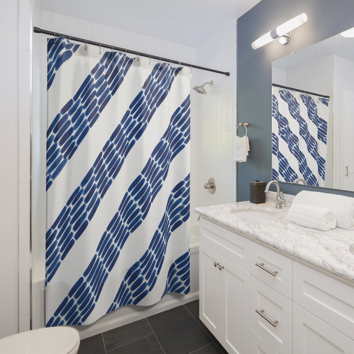 Diagonal indigo ink dashes and broad white stripes shower curtain beside a white vanity