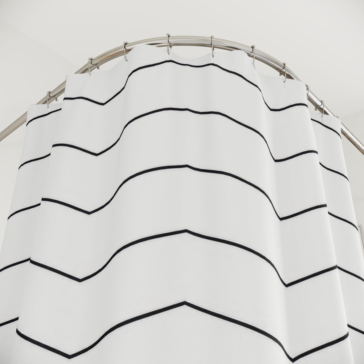 Fine black chevron rows on an open white ground shower curtain with close-up print, hooks, and folds