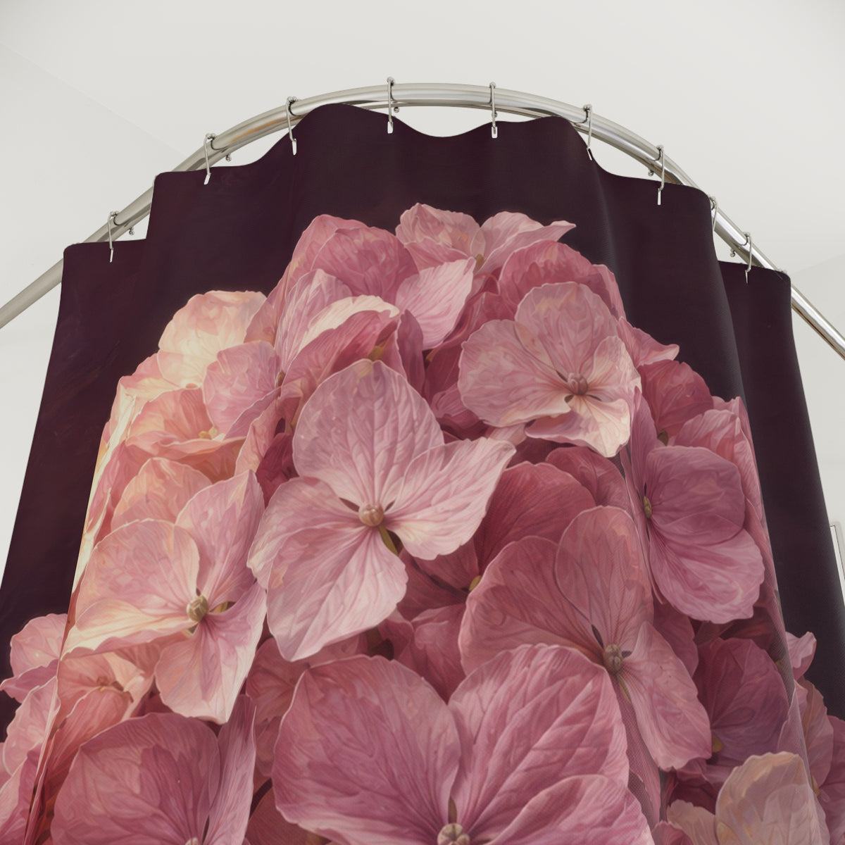 One pink hydrangea bloom with green leaves on aubergine shower curtain with close-up print, hooks, and folds
