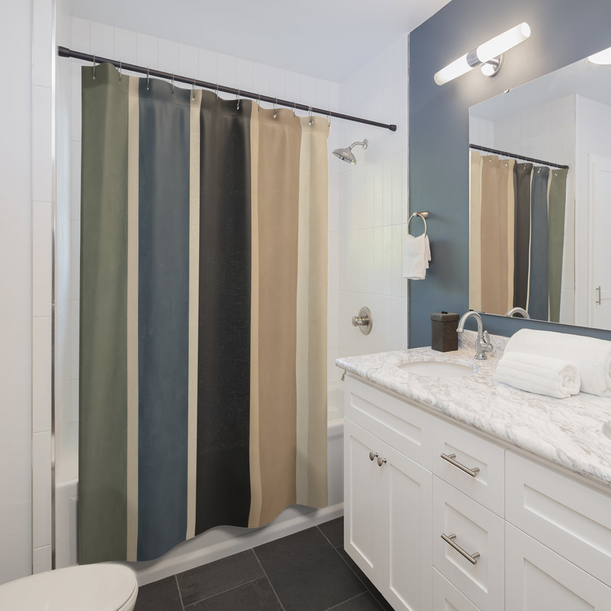 Wide vertical stripes in sage blue charcoal tan and cream shower curtain beside a white vanity